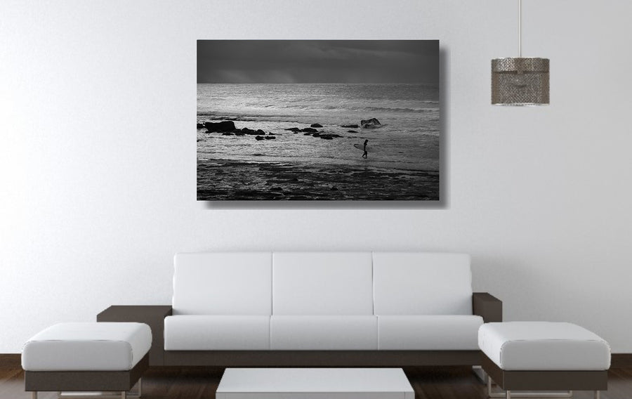 Black and white photograph of a surfer entering the water at Mollymook NSW