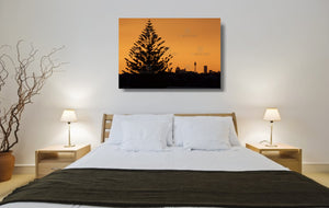 An acrylic print of the Sydney city skyline at sunset in hanging in a bed room setting