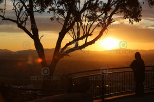A photograph of a lone person watching the sunset from a lookout at Tamworth in NSW.